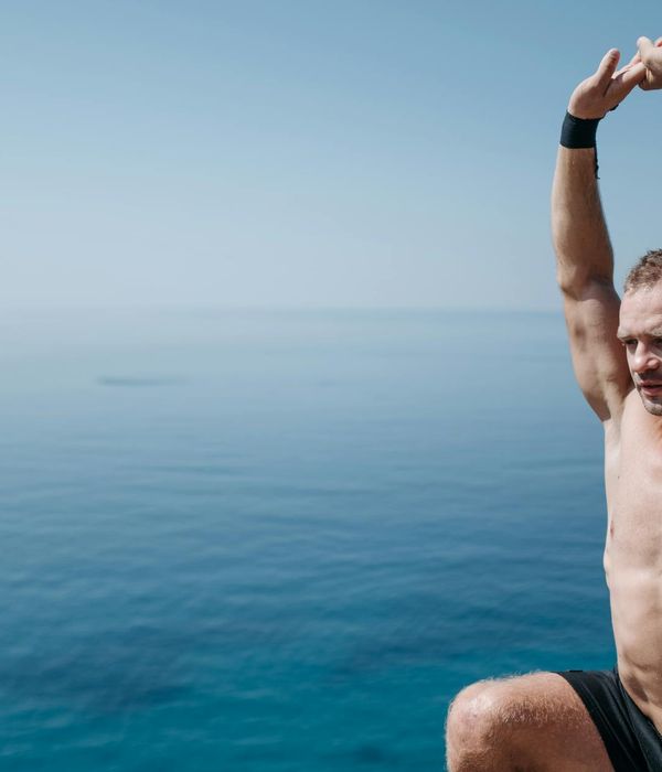 Man stretching outdoors with a serene natural background and yellow light effects.